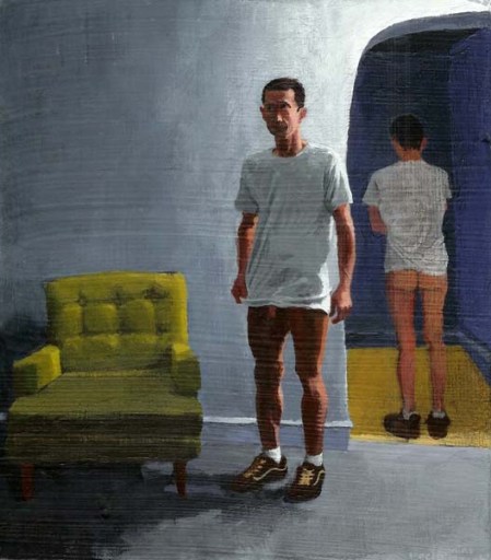Standing erect man with no pants, a white shirt, and shoes next to agreen chair